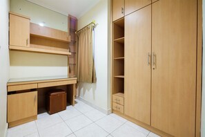 Compact room with a desk, wardrobe, and tiled floor.