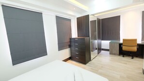 Quarto moderno com cama, cômoda, escrivaninha e cadeira.