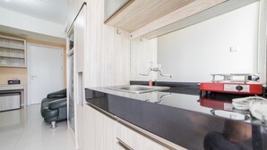 A modern kitchen with a black countertop, stainless steel sink, and a red appliance. - Modern Apartment Near Cihampelas at Parahyangan Residence (Bandung)
