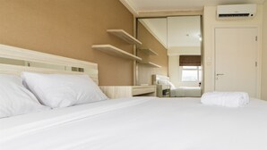 A hotel room with a large bed, a bedside table, a mirror, and a wardrobe. - Modern Apartment Near Cihampelas at Parahyangan Residence (Bandung)