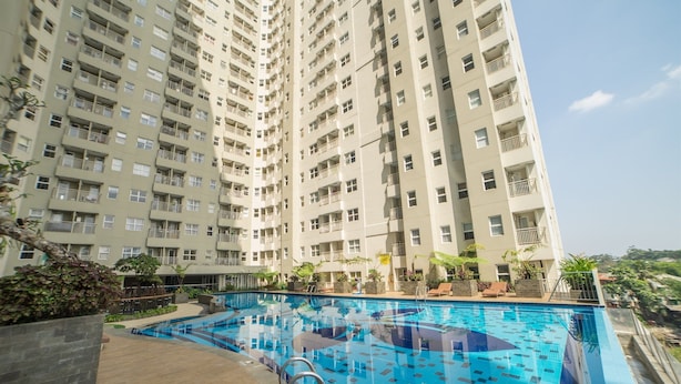 A high-rise building with a swimming pool on the ground level. - Modern Apartment Near Cihampelas at Parahyangan Residence (Bandung)