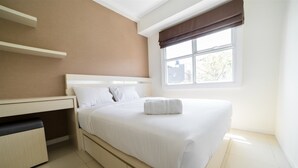 Una camera da letto ordinata con un letto, un comodino e una finestra che mostra edifici.