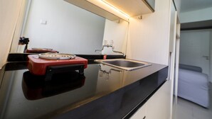 Una cucina moderna con un piano di lavoro nero, un elettrodomestico rosso, un lavello in acciaio inossidabile e uno specchio sopra il lavello.