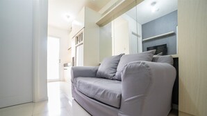 Un soggiorno moderno con un divano grigio, una televisione a schermo piatto e un mobiletto in legno.