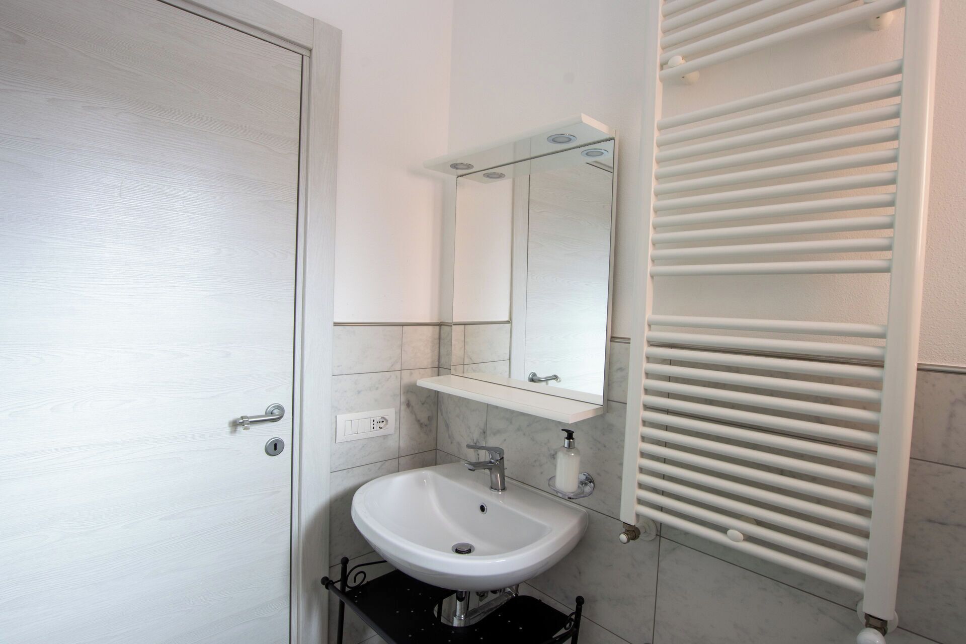 A bathroom with a white sink, a mirror, and a towel rack.