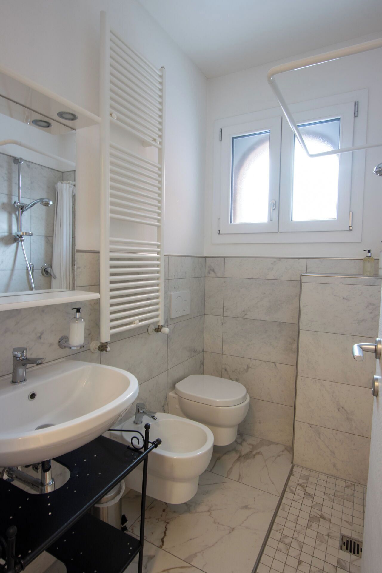 A bathroom with a white sink, a bidet, a toilet, and a shower.