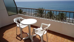 Un balcone con vista sull'oceano, con un tavolino e due sedie.