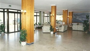 Un'ampia hall con imponenti colonne in legno, comodi posti a sedere e grandi finestre che lasciano entrare la luce naturale.
