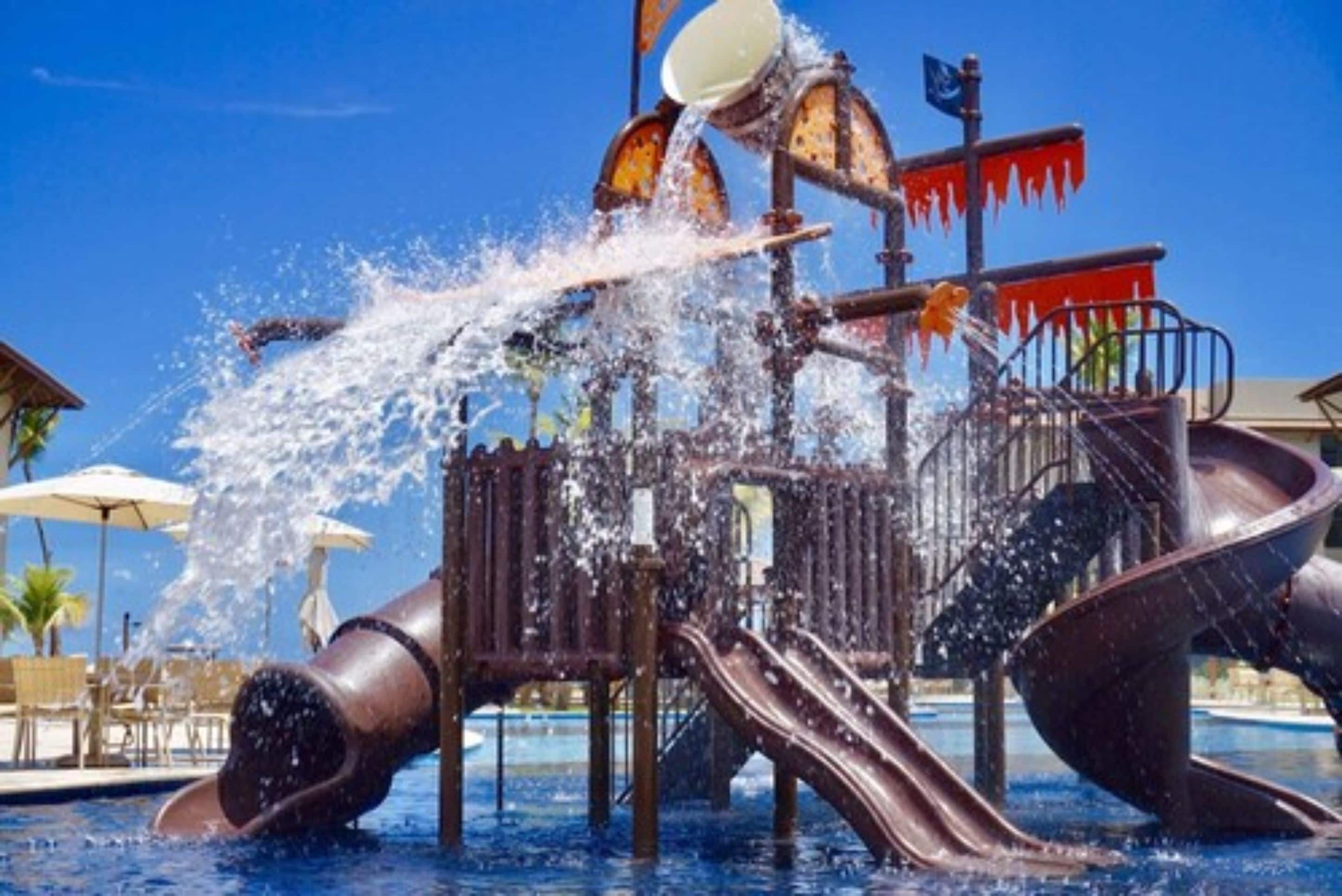 A water play area with slides and water jets over a pool.