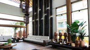 A spacious lobby with a sofa, wooden benches, and potted plants. - Samoa Beach Resort (Ipojuca)