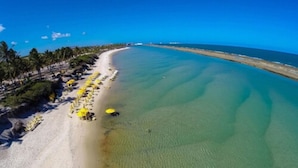 A beach with clear turquoise water, a sandy shore, and yellow umbrellas. - Samoa Beach Resort (Ipojuca)