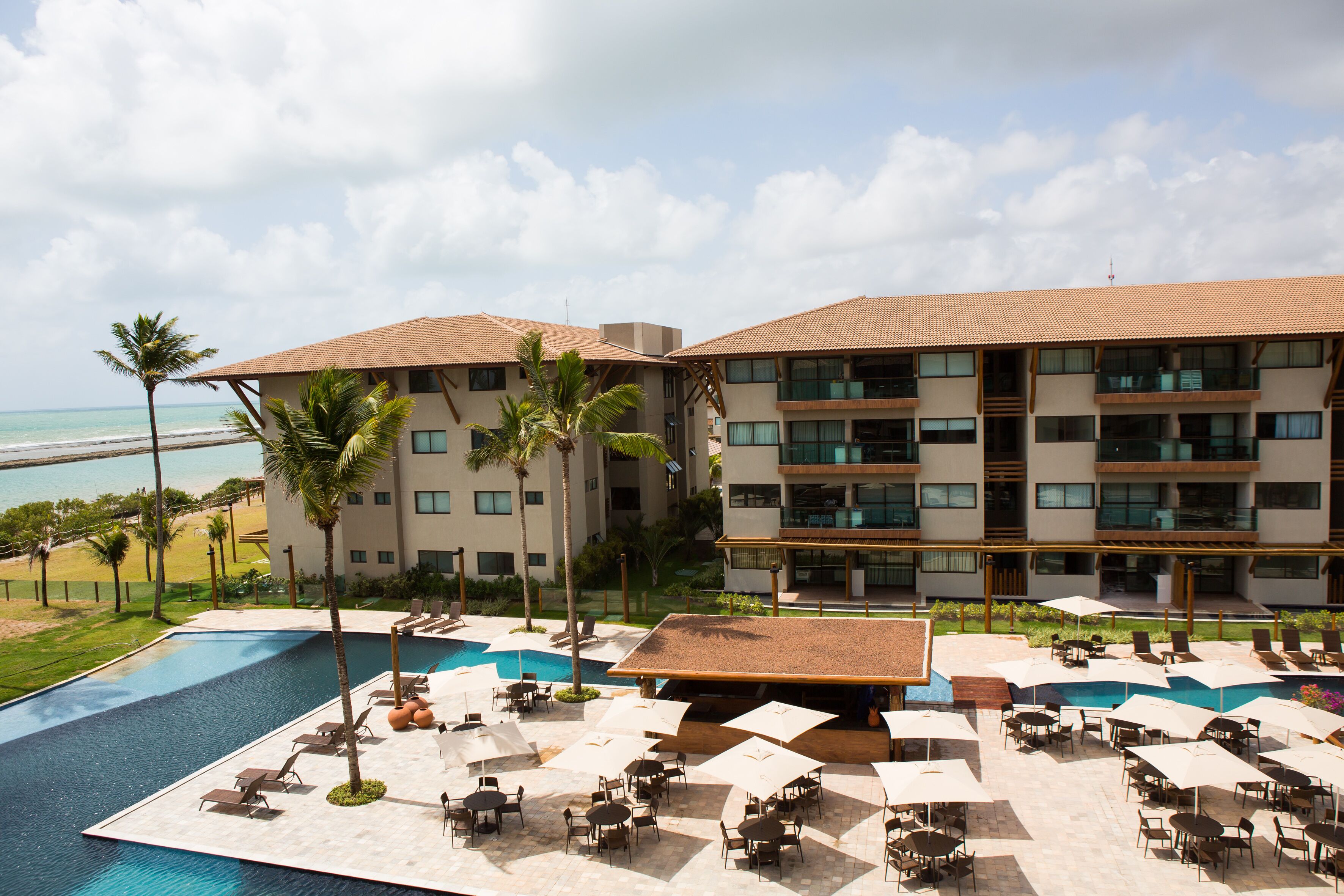 A hotel with a pool, outdoor seating, and a view of the beach.