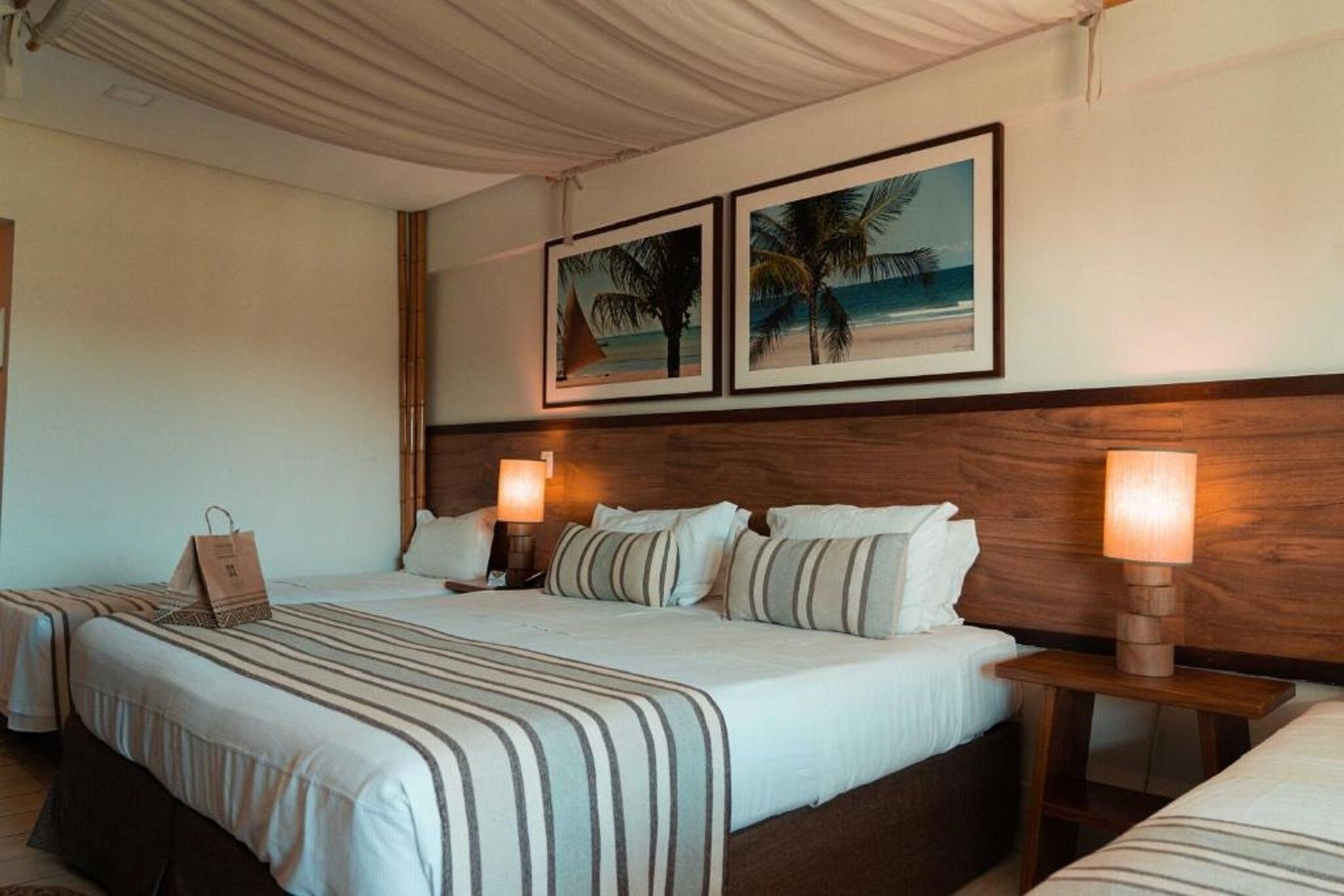 A hotel room with a large bed, two bedside tables with lamps, and two framed pictures on the wall.
