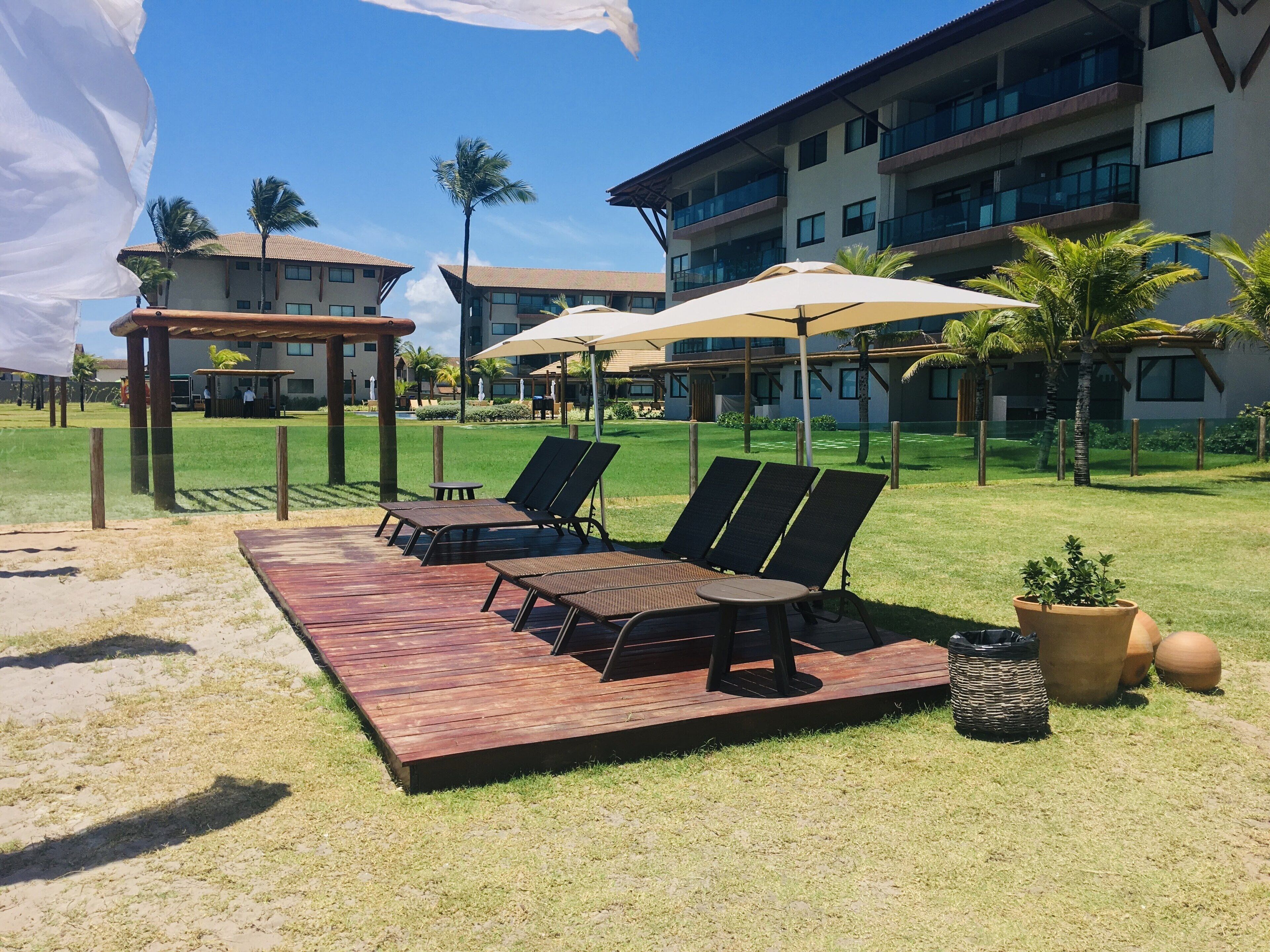 A resort with outdoor lounge chairs, umbrellas, and a pool area.
