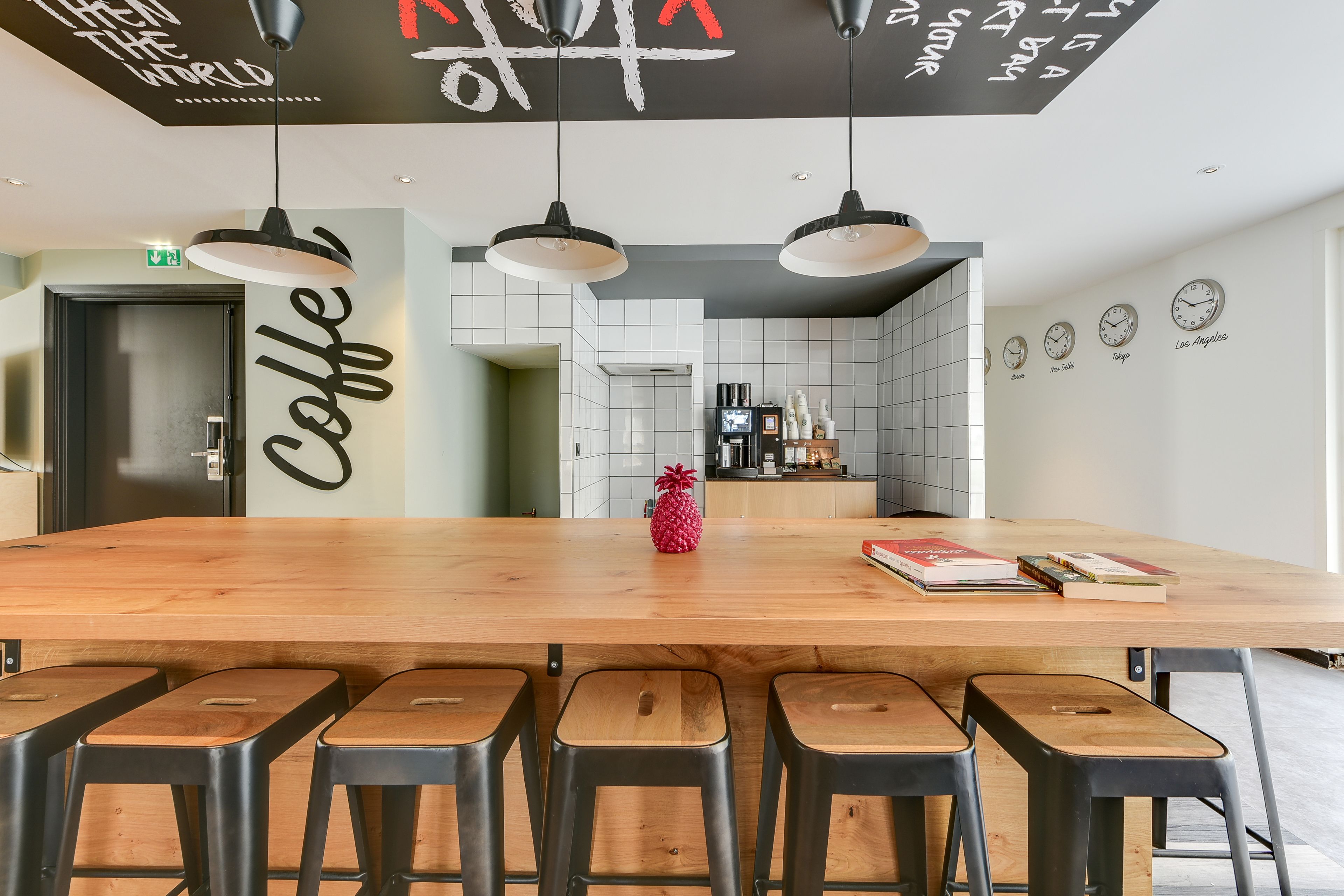 Une cuisine moderne avec un îlot central en bois, des tabourets de bar et une décoration à thème ananas.