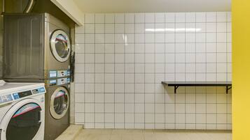 A laundry room with two washing machines, a bench, and tiled walls.