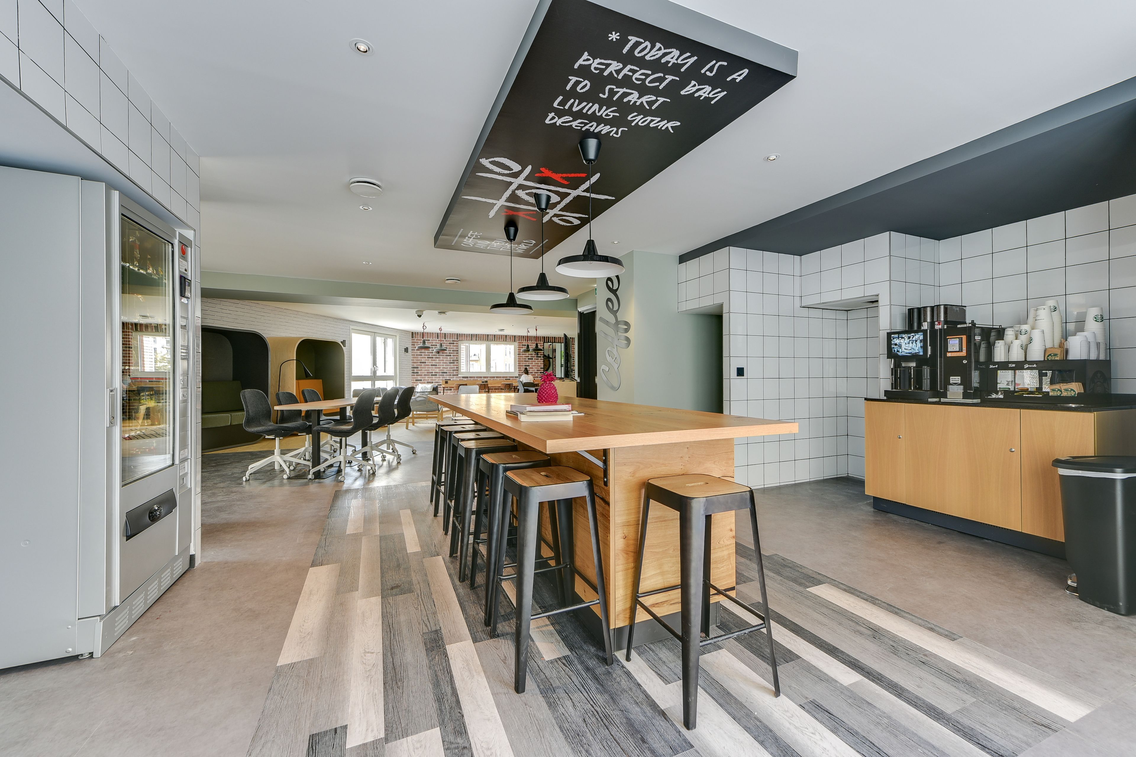 A modern kitchen with a wooden bar area, a built-in oven, and a coffee machine.