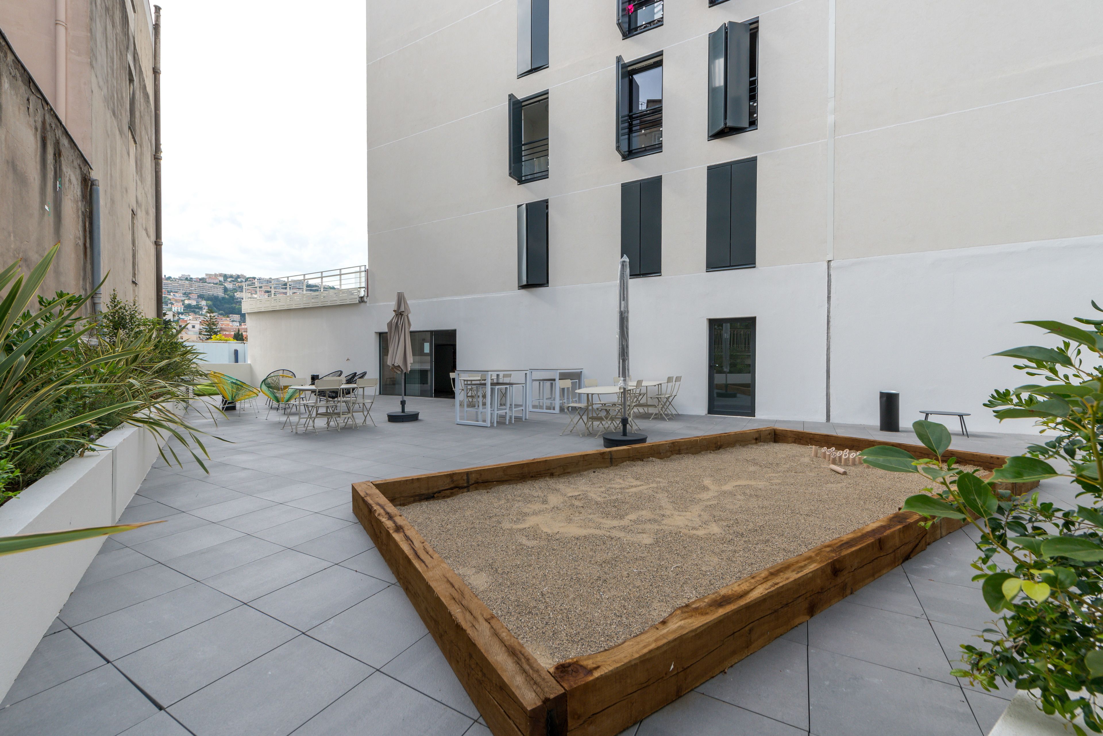 Une terrasse sur le toit, agrémentée d’un jardinier en bois, de mobilier d’extérieur et offrant une vue sur le paysage urbain.