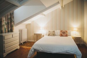 A bedroom with a large bed, two bedside tables, a dresser, and a radiator. - Alamar Salinas - Hostel (Castrillon)