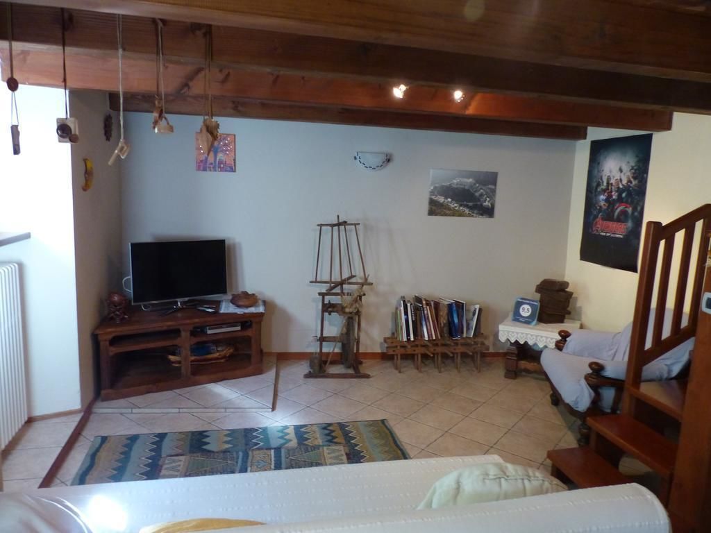 A cozy living room with a television, wooden furniture, a bookshelf, and a painting on the wall.
