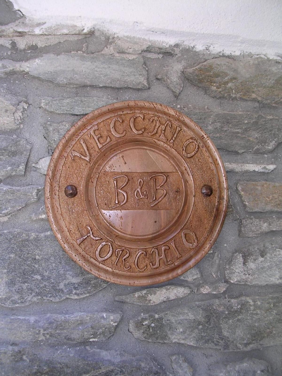 A metal plaque with embossed text on a stone wall.