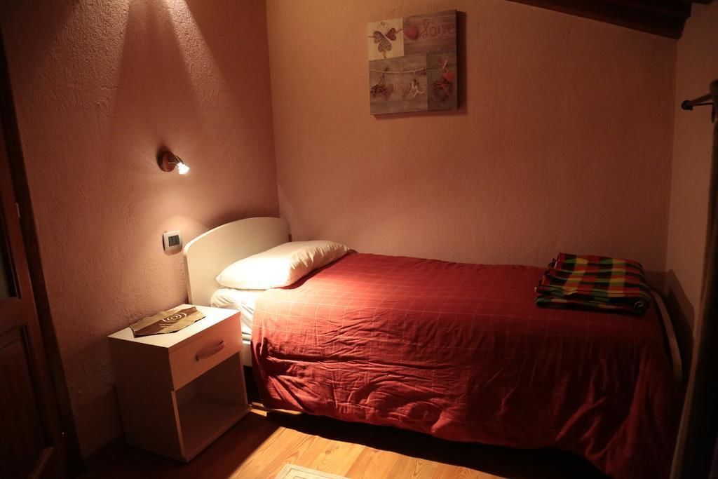 Un dormitorio pequeño y acogedor con una cama individual, una mesita de noche y una lámpara de pared.