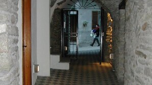A stone-walled corridor with a checkered floor leading to a door. - b&b Vecchio Torchio (Bard)