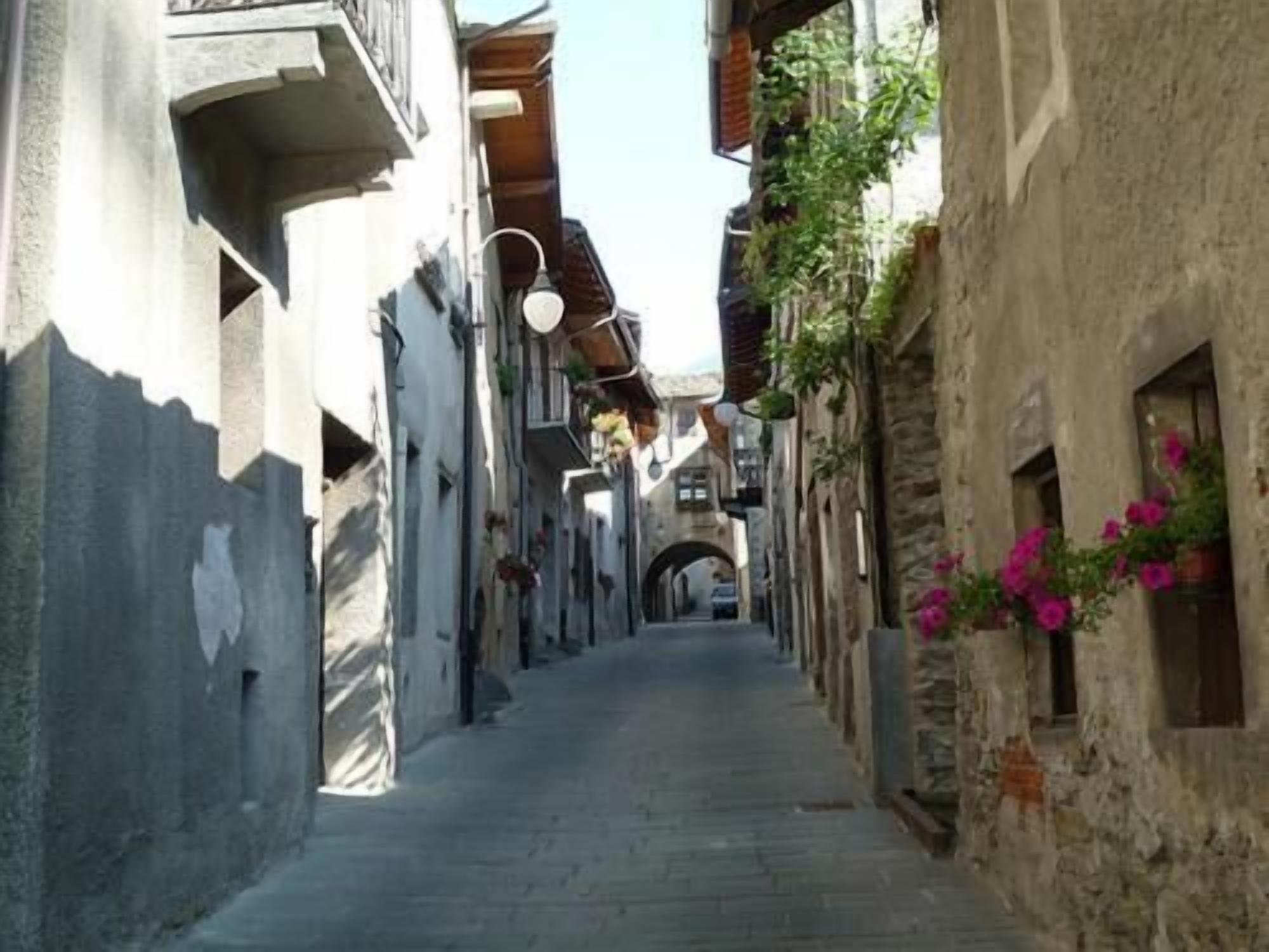 Un carrer estret amb edificis a ambdós costats, amb balcons i caixes de flors.
