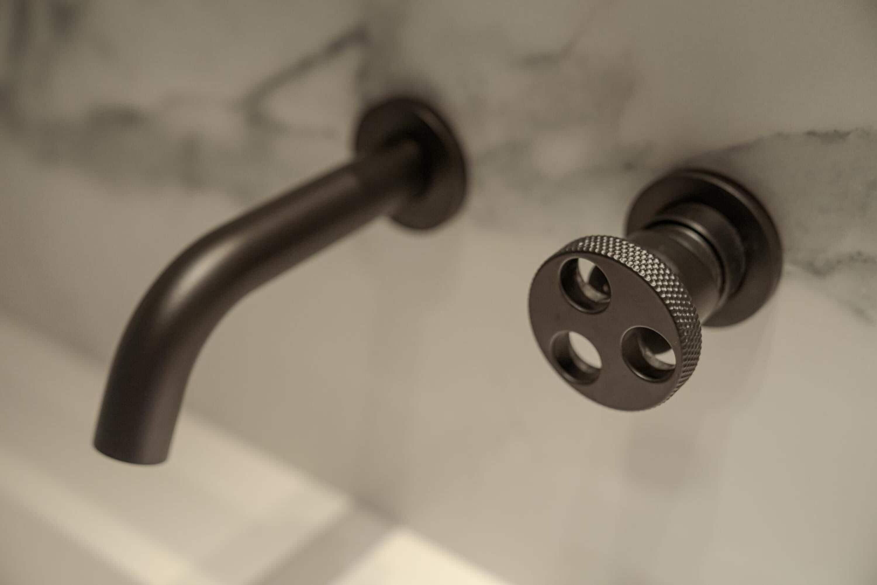 A close-up of a bathroom faucet with a curved spout and a textured handle.