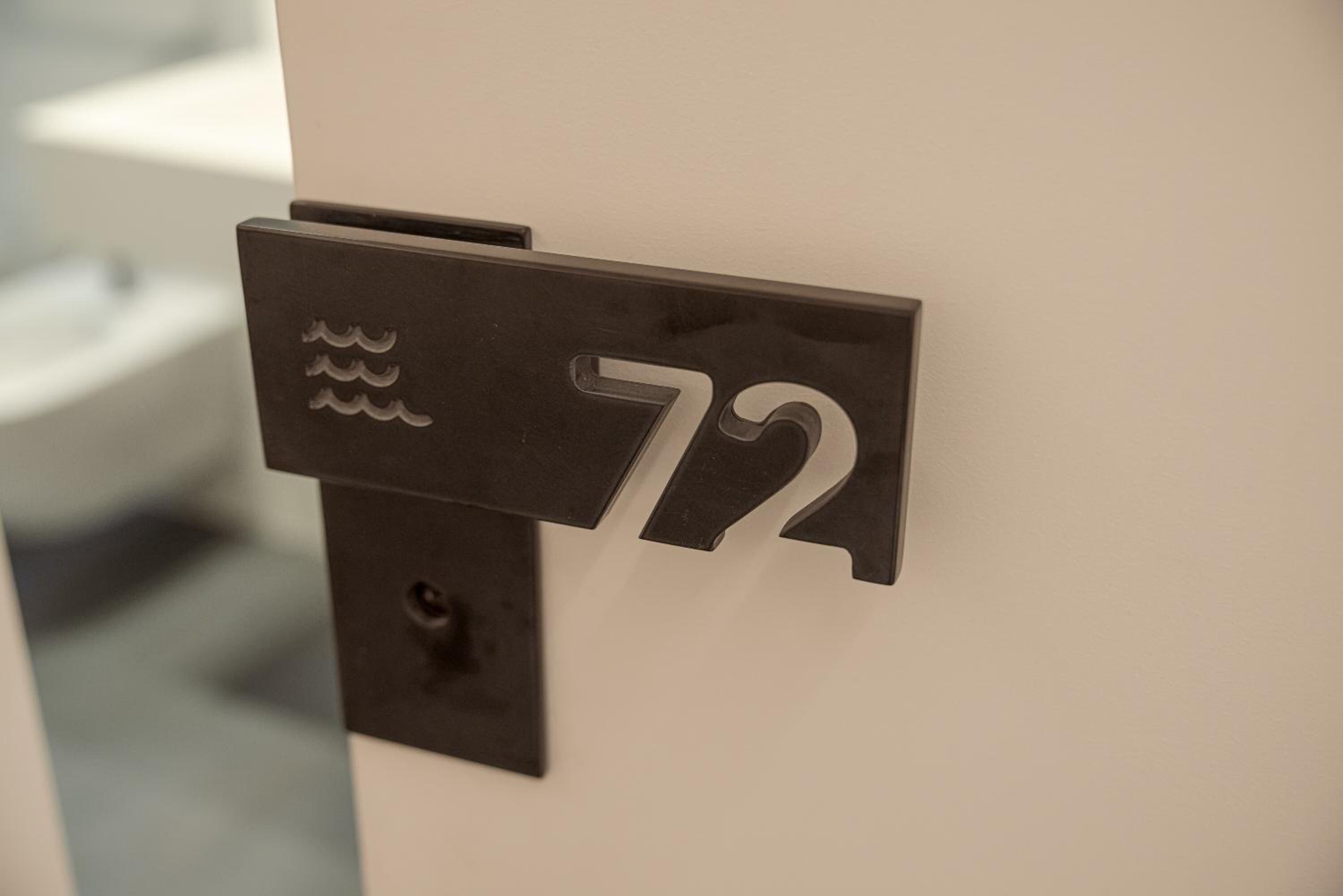 Placa de metal preta com o número 72 numa parede branca.