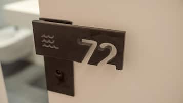 Placa de metal preta com o número 72 numa parede branca.