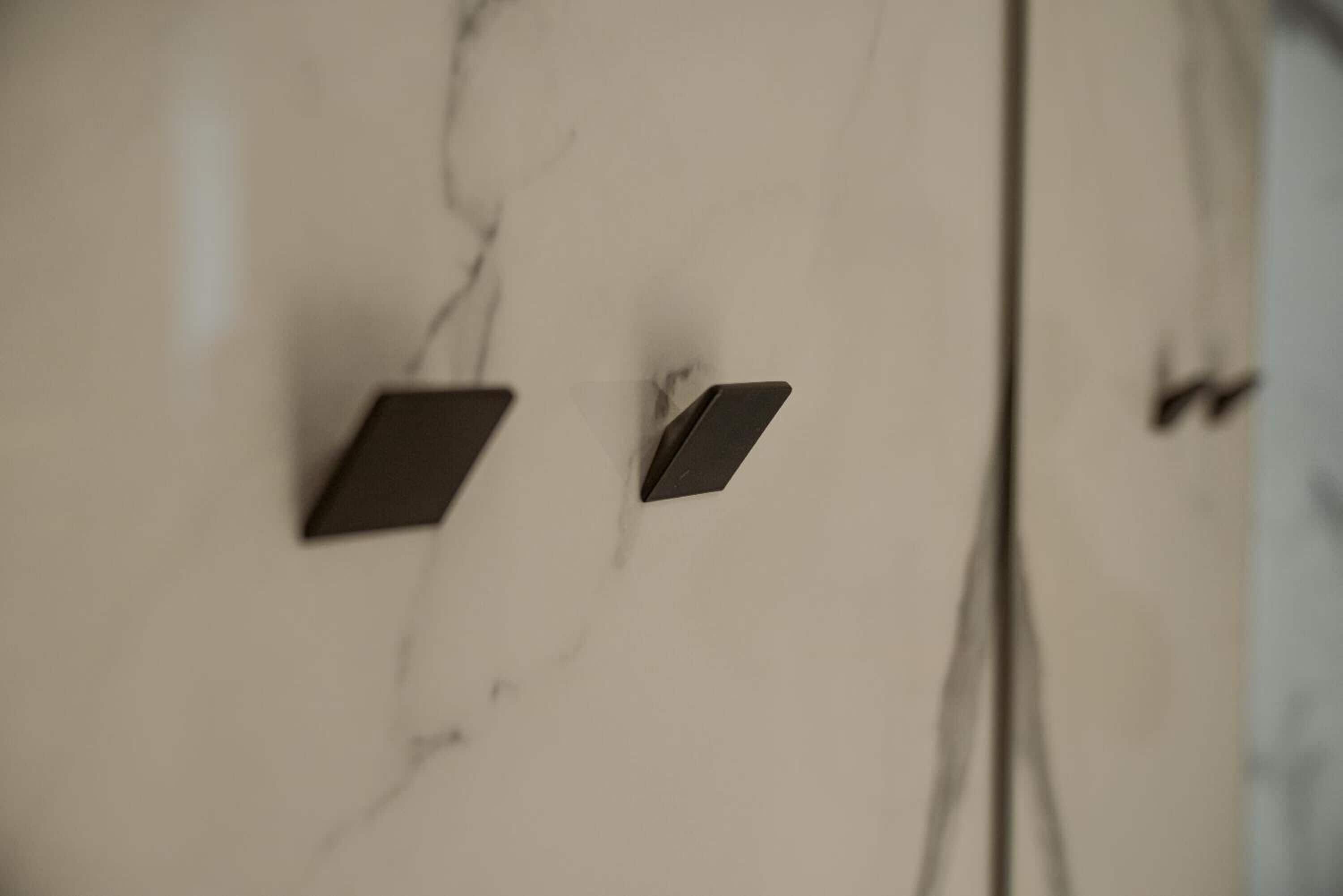 A close-up of a marble wall with two dark rectangular objects, possibly electronic devices or controls.
