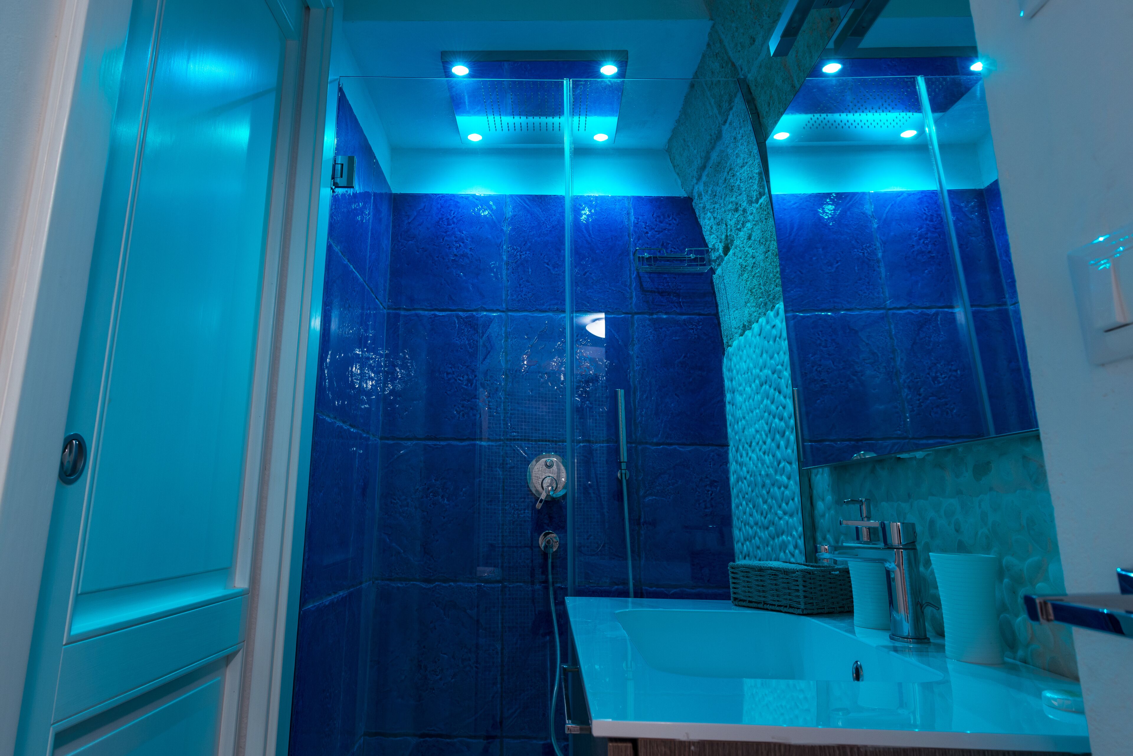 Ein Badezimmer mit Duschkabine aus Glas, Waschbecken und Spiegel.