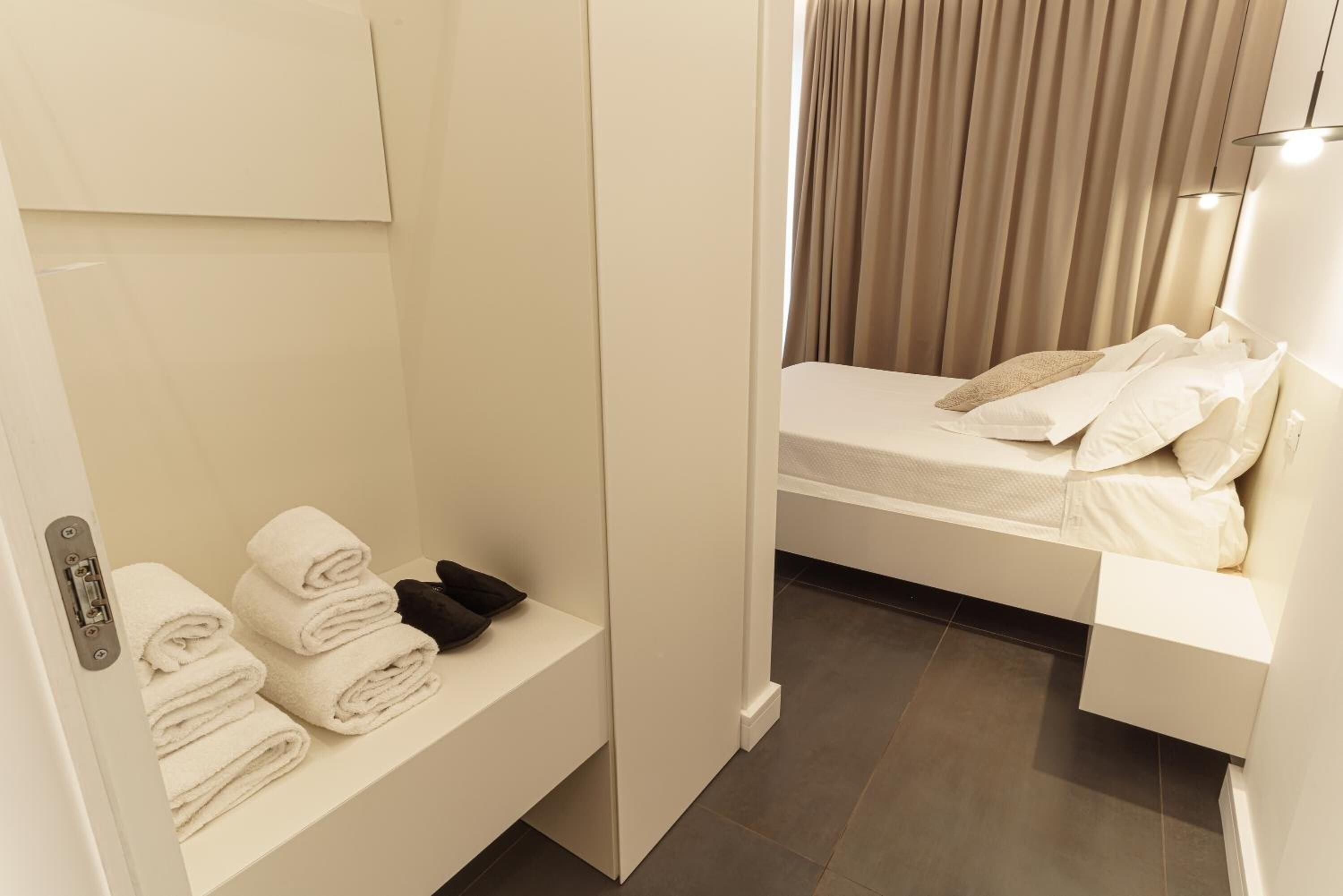 Una habitación de hotel con cama, un pequeño rincón de descanso con toallas y zona de ducha.