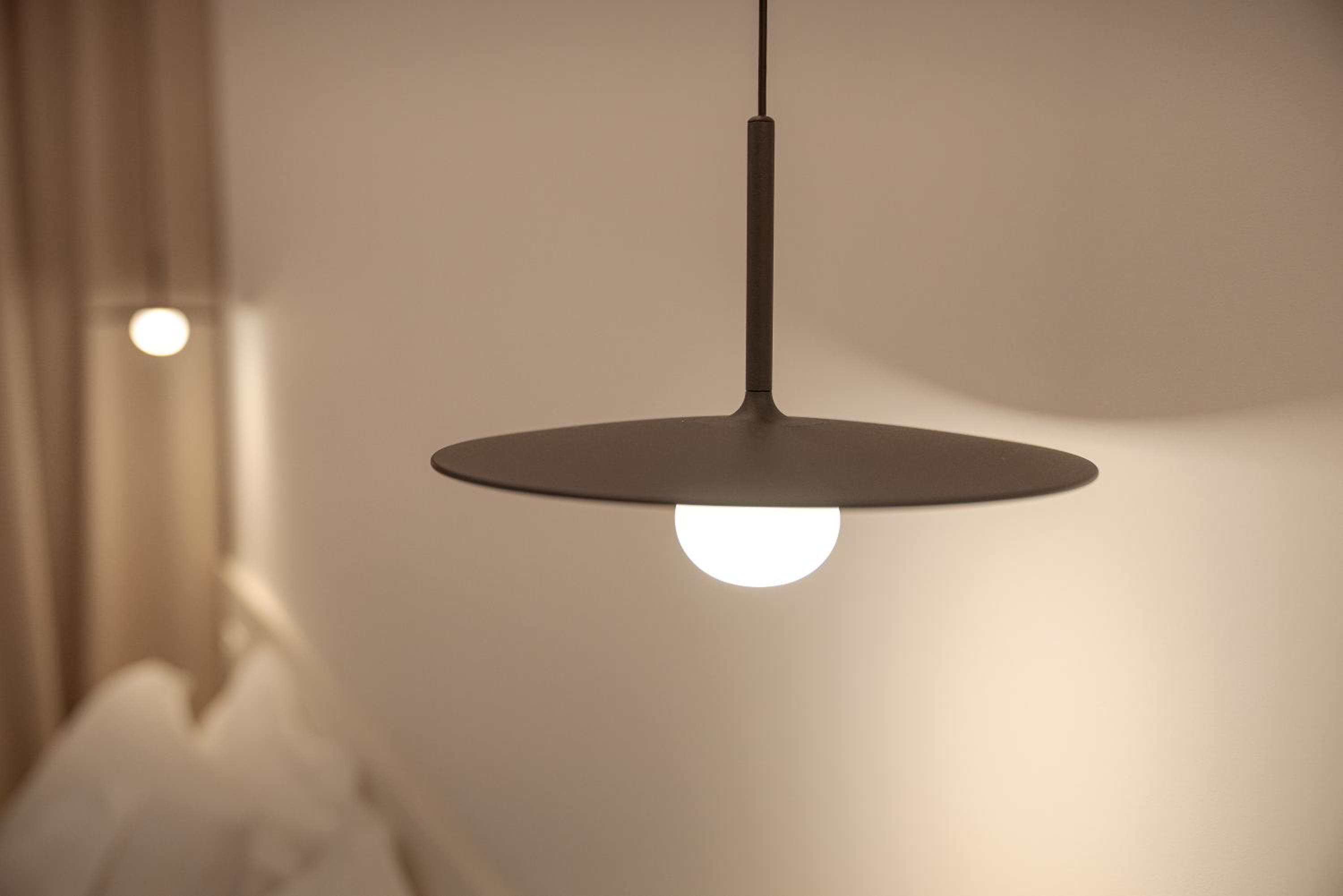 Eine Pendelleuchte mit einer kugelförmigen Glühbirne, die an einem schlichten, geraden Stab befestigt ist.