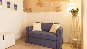 Ein Zimmer mit einem karierten Sofa, einem weißen Schrank und einem an der Wand befestigten Regal mit einer Pflanze.