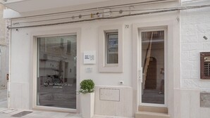 Ein Gebäudeeingang mit einem großen Glasfenster, einem kleinen Blumentopf und einem Schild mit der Aufschrift 'AQP'.