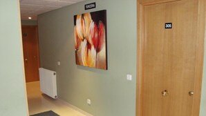 Un pasillo con un radiador, una puerta con la etiqueta “TERCERA” y un cuadro abstracto grande en la pared.