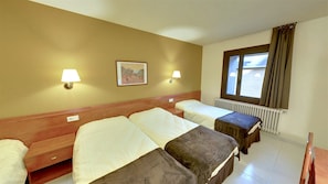A hotel room with two beds, a window with curtains, a radiator, and two wall-mounted lamps. - Hotel Guineu (Pas de la Casa)