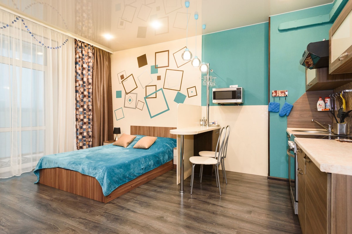 A modern bedroom with a bed, bedside table, and a desk area.