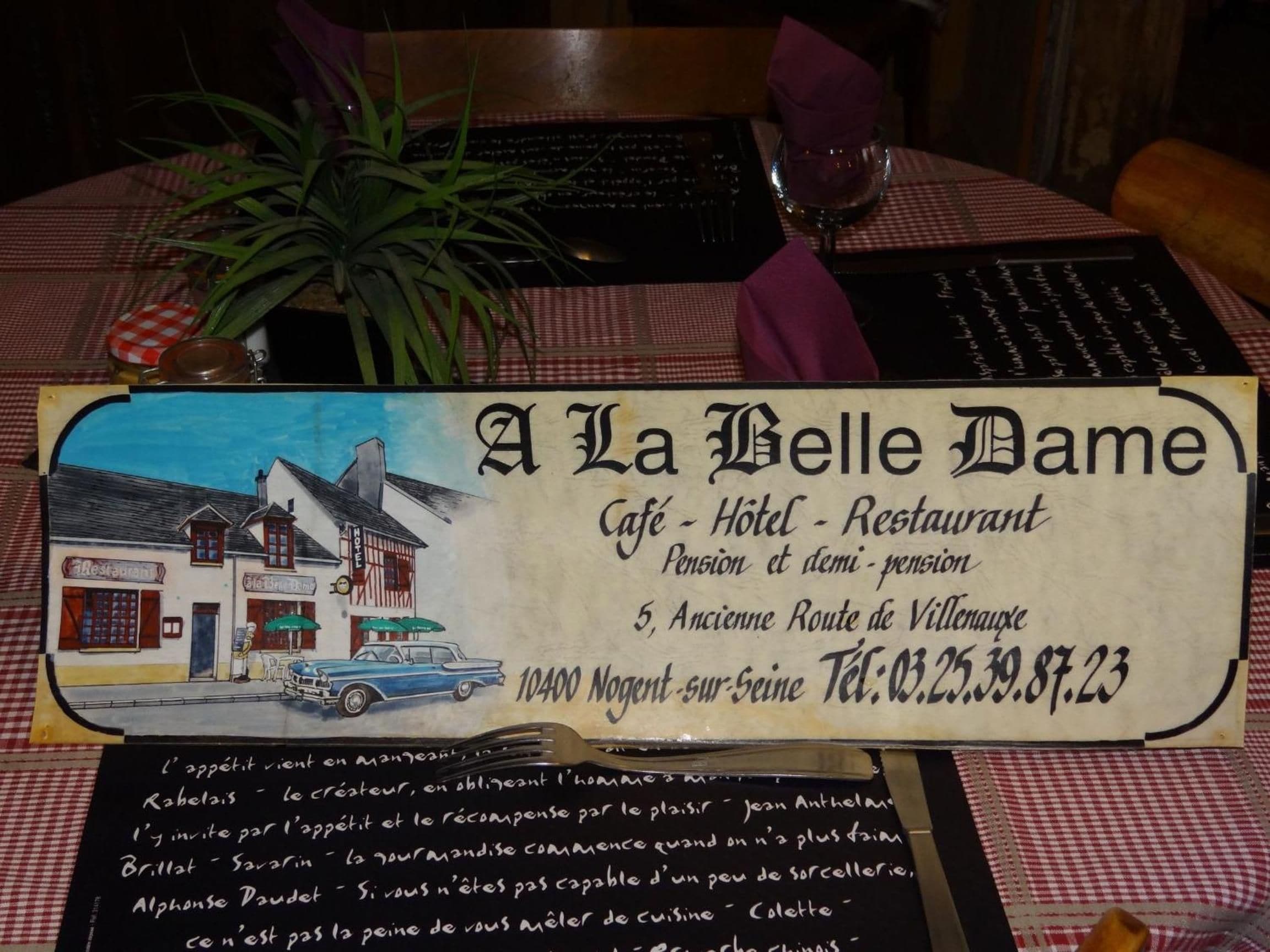 A hotel sign with a vintage illustration of a building, the name 'A La Belle Dame', and contact information.