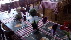 Un restaurante con manteles a cuadros, paredes de madera y pizarras con la carta.