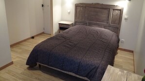 Un dormitorio con cama, mesita de noche y cabecero de madera.