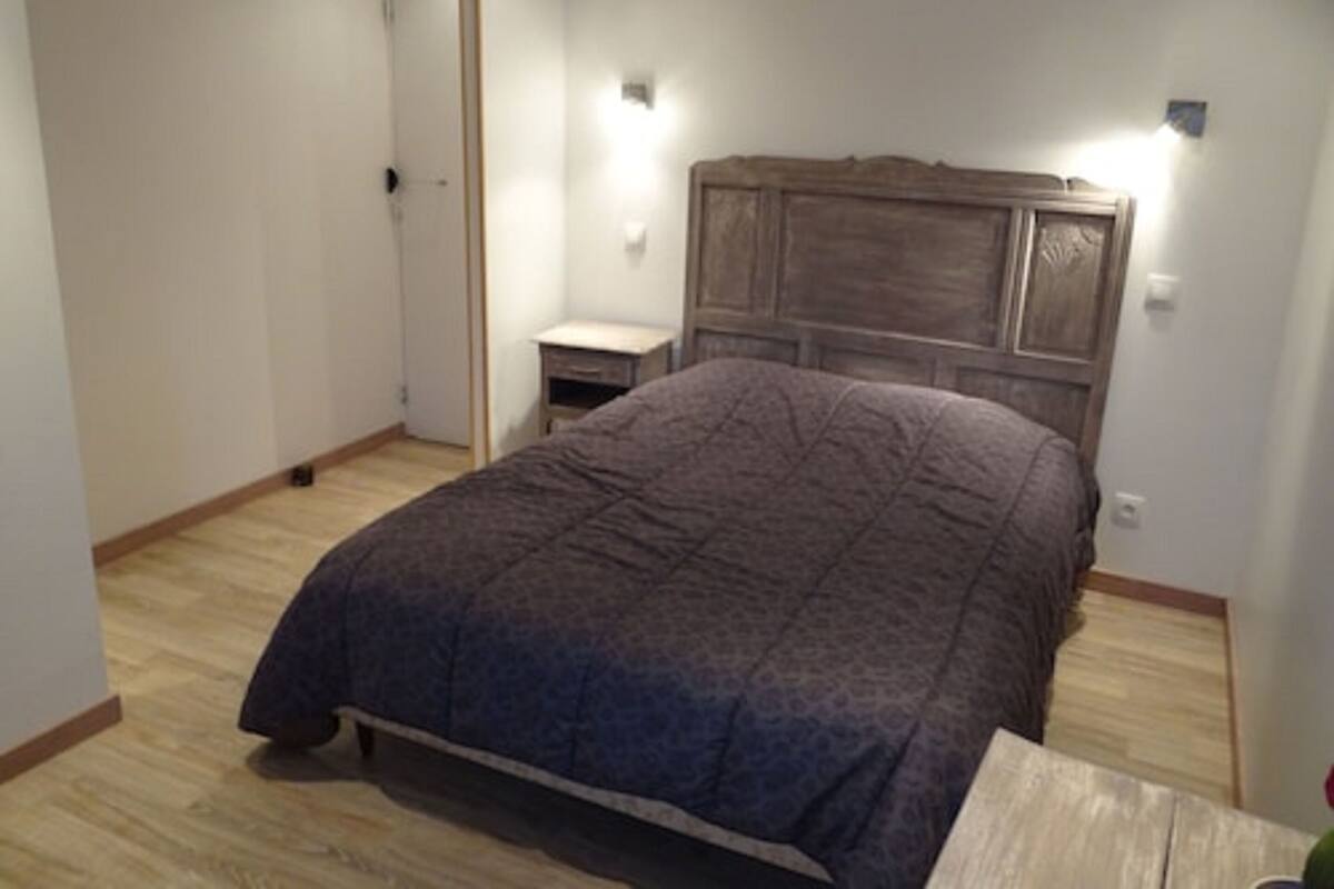 Un dormitorio con cama, mesita de noche y cabecero de madera.