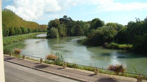 Un río con un camino pavimentado a su lado, bordeado de follaje y árboles.