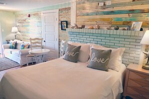 Un dormitorio con una cama, una mesita de noche, un tocador, una silla y una pequeña mesa.