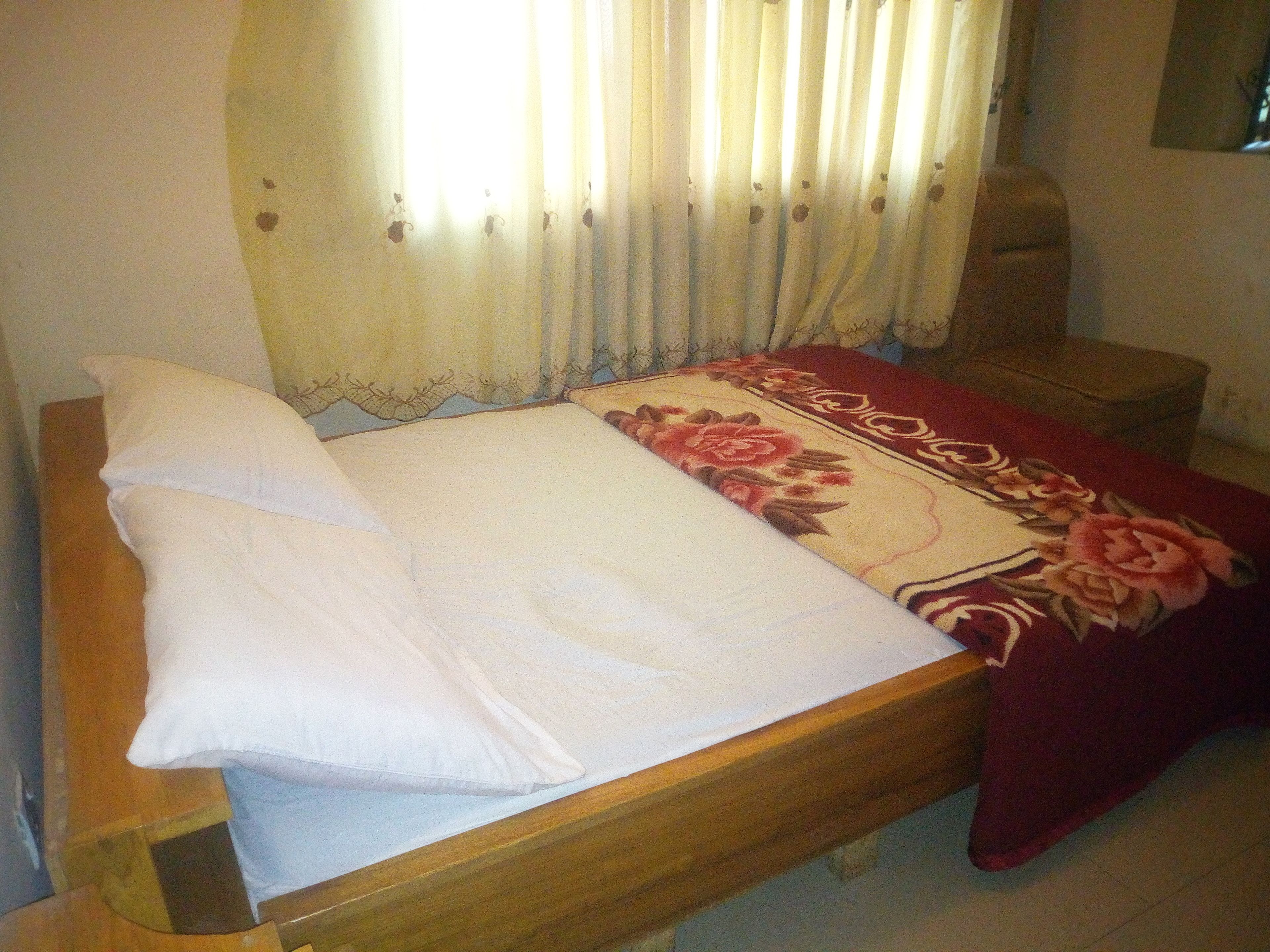 A single bed with white bedding and a floral-patterned throw blanket.