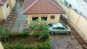 A residential area with a house featuring a sloped roof and a car parked in the driveway. - Blue Banana Resorts (Abeokuta)