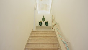 A staircase with a textured ceiling and a decorative rope on the right side. - Casa Meliò (Polignano a Mare)