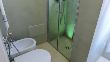 Un baño con ducha envuelta en vidrio, un inodoro blanco y un bidé.